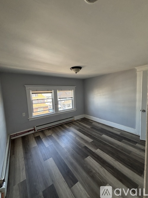 A room with a window and wooden flooring.