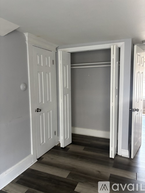 A room with a white door and a wooden floor.