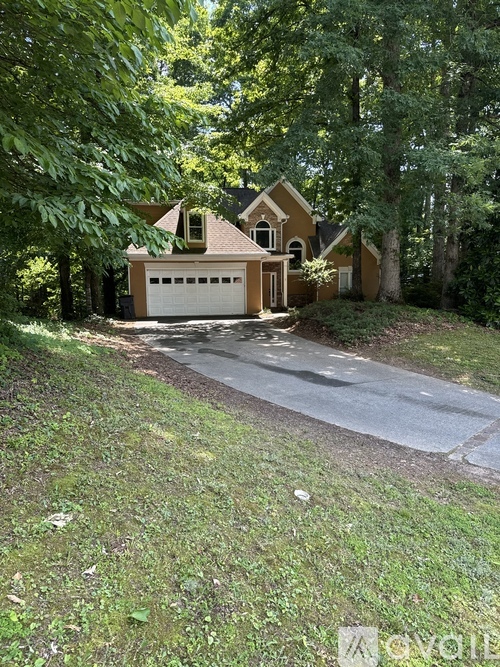A house with a garage is surrounded by trees.