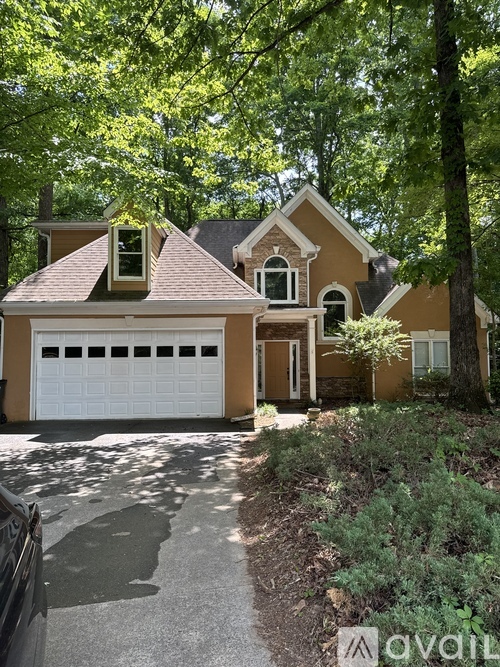 A house with a white garage door is surrounded by greenery.