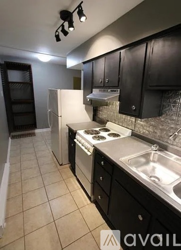 A kitchen with black cabinets and a white fridge.