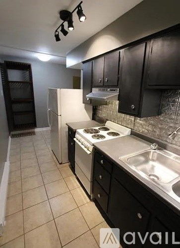 A kitchen with black cabinets and a white fridge.