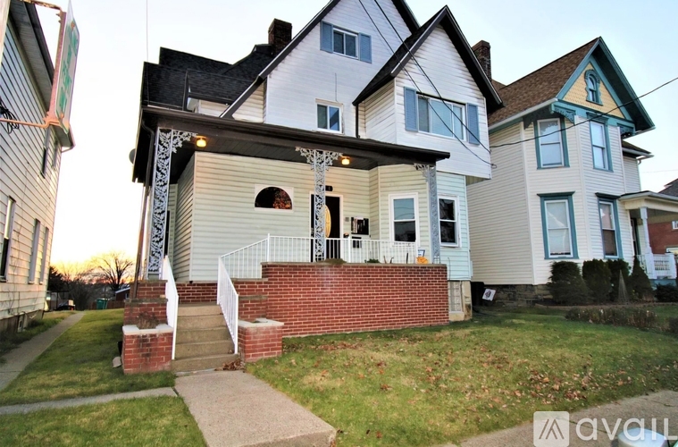 A house with a white and grey exterior and a red brick wall.