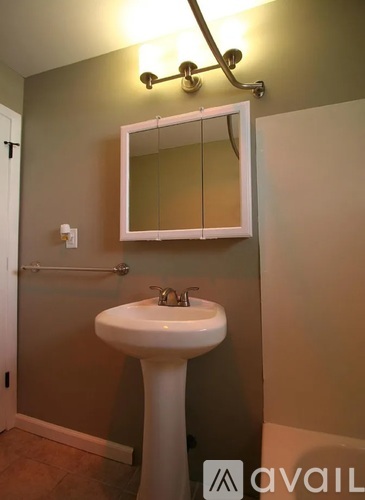 A bathroom with a white pedestal sink and a mirror above it.