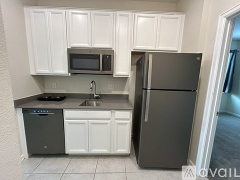 A kitchen with white cabinets and a black fridge.