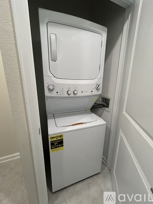 A white dryer is in a small space between a wall and a door.