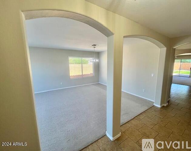 A spacious room with a carpeted floor and arched doorways.