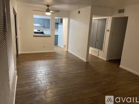 A spacious room with wooden flooring and a ceiling fan.