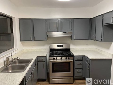 A kitchen with a stove, sink, and cabinets.