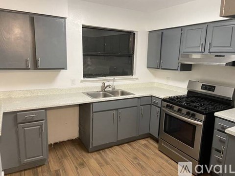 A kitchen with a stove, sink, and cabinets.