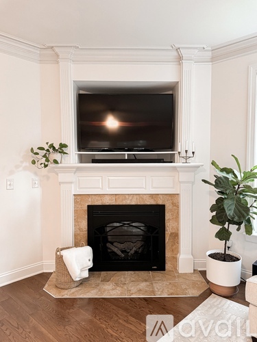 A living room with a fireplace and a television mounted above it.