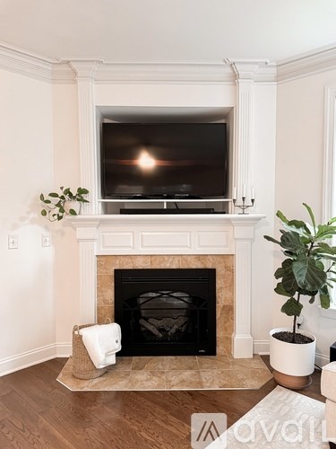 A living room with a fireplace and a television mounted above it.