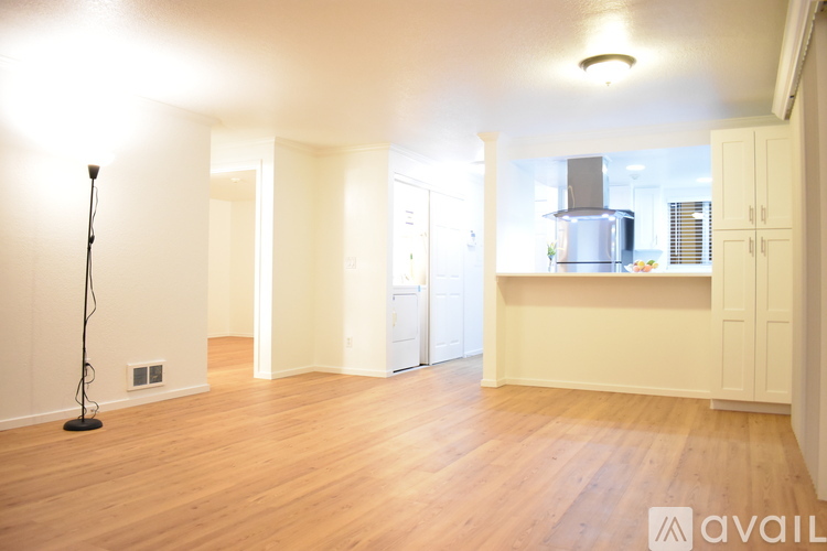 A spacious room with wooden floors and white walls.