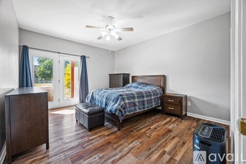 A bedroom with a bed, nightstand, and a ceiling fan.