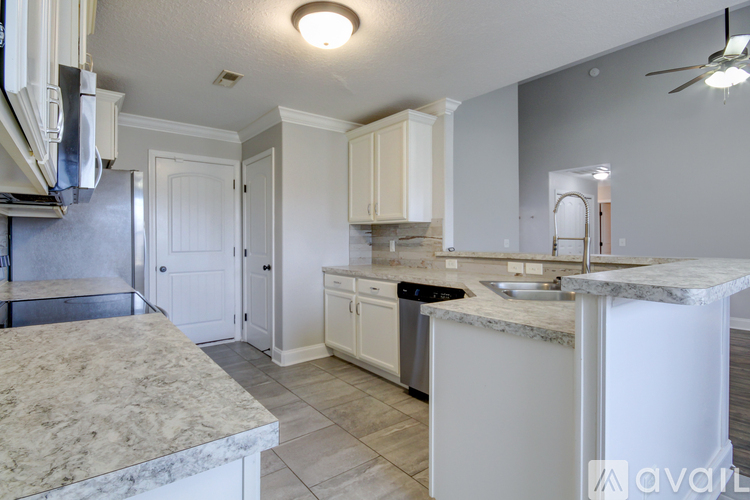 A kitchen with white cabinets and a marble countertop.