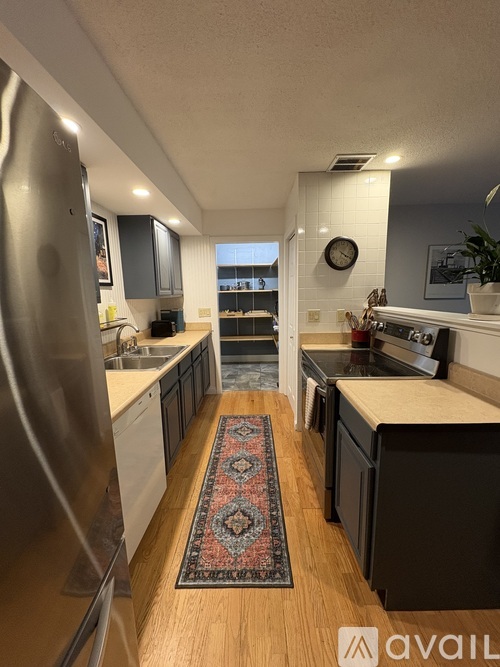 A kitchen with a rug on the floor and a refrigerator on the left.
