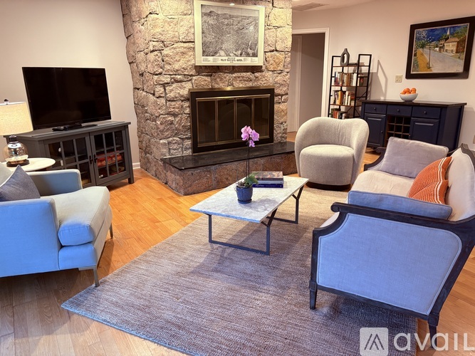 A living room with a stone fireplace and a grey sofa.