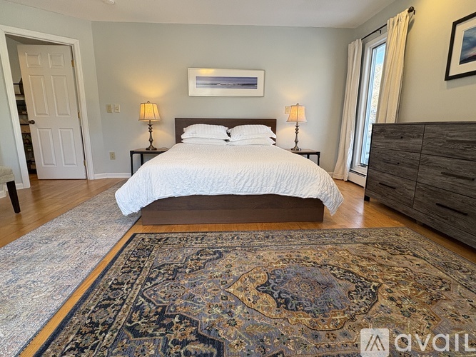 A bedroom with a large bed and a rug on the floor.