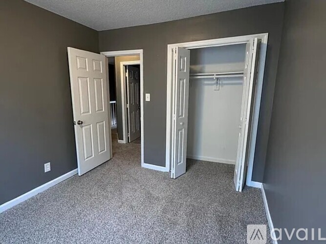 A room with two doors, one open, and carpeted flooring.