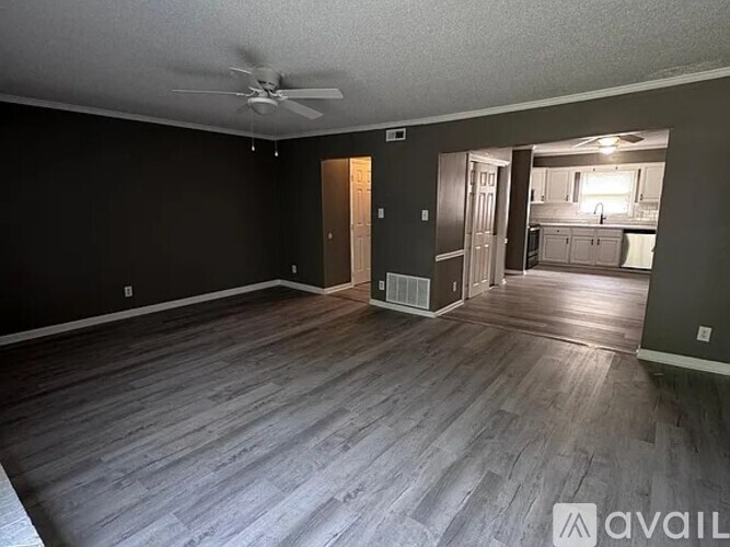 A spacious room with wood flooring and a ceiling fan.