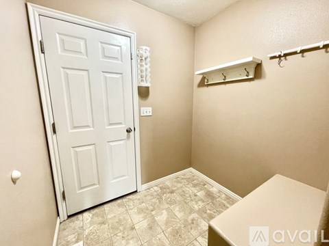 A white door is in a room with a towel rack and a toilet.