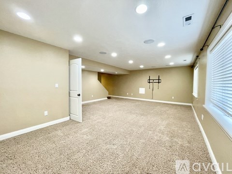 A spacious room with beige carpeting and a white door.