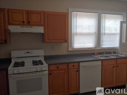 A kitchen with a white stove and wooden cabinets.