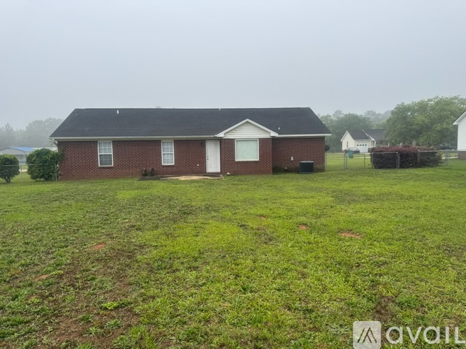 A house with a white door and windows is surrounded by a grassy field.