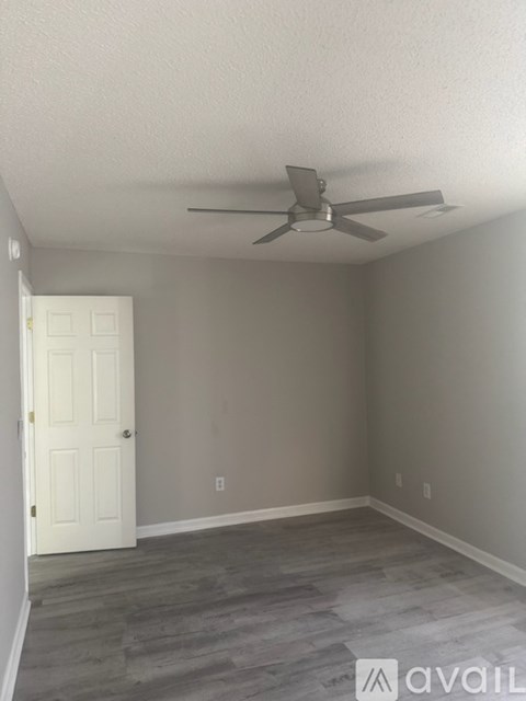 A room with a ceiling fan and a door.