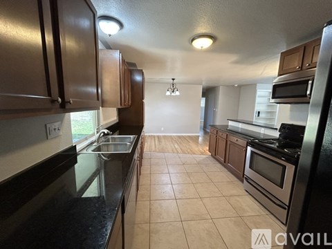 A kitchen with brown cabinets and black countertops.