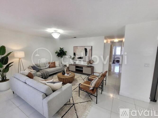 A modern living room with a grey sofa, wooden coffee table, and a large painting on the wall.