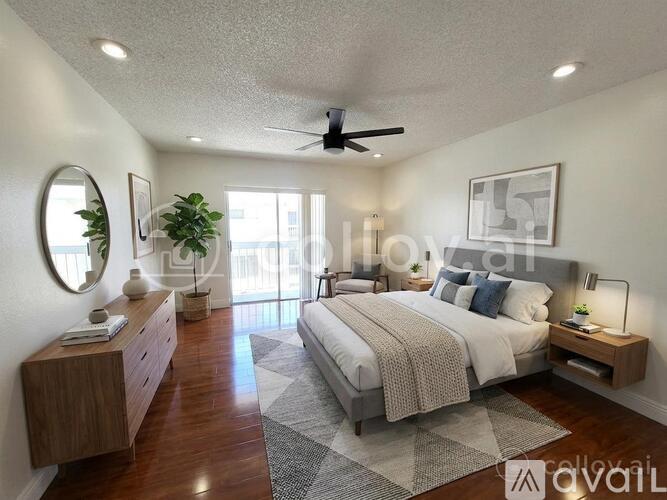 A bedroom with a large bed, a ceiling fan, and a mirror on the wall.