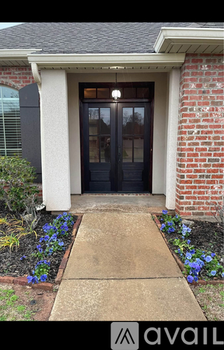 A house entrance with a black door and a concrete walkway.