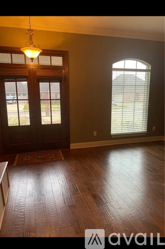 A room with wooden floors and a window with blinds.