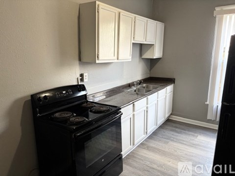 A kitchen with a black stove top oven and white cabinets.
