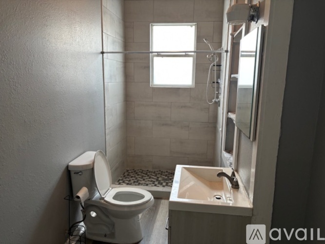 A small bathroom with a toilet, sink, and shower.