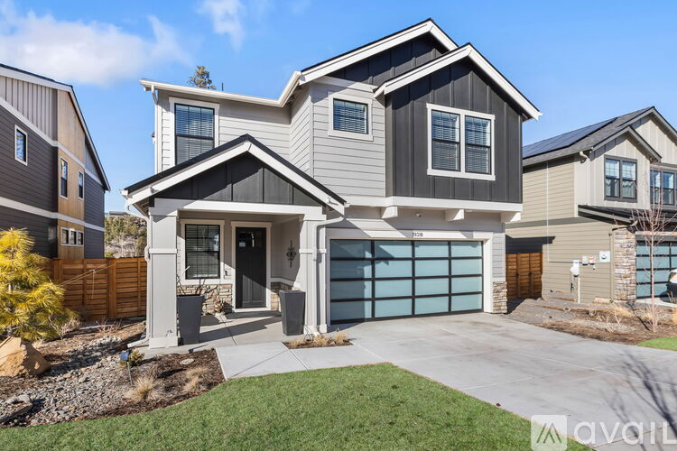 A modern house with a grey and white exterior and a large front yard.