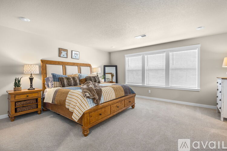 A bedroom with a large bed, a nightstand with a lamp, and a dresser with a mirror.