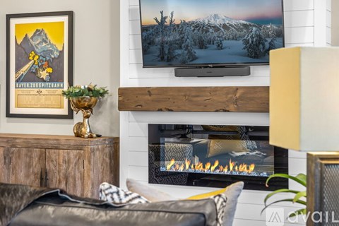 A cozy living room with a fireplace and a painting of a snowy mountain landscape on the wall.