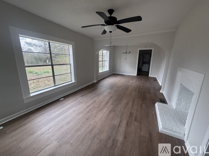 A spacious room with wooden flooring and a ceiling fan.