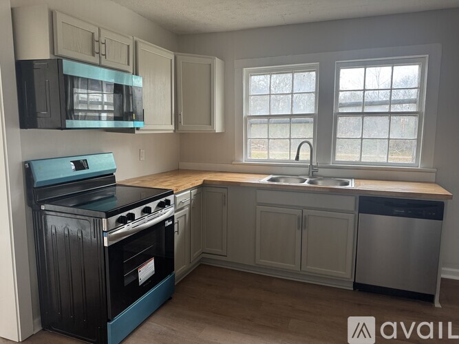 A kitchen with a blue stove top oven and a white dishwasher.
