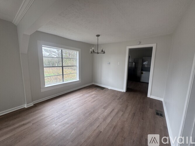 A room with wooden flooring and a window overlooking a field.