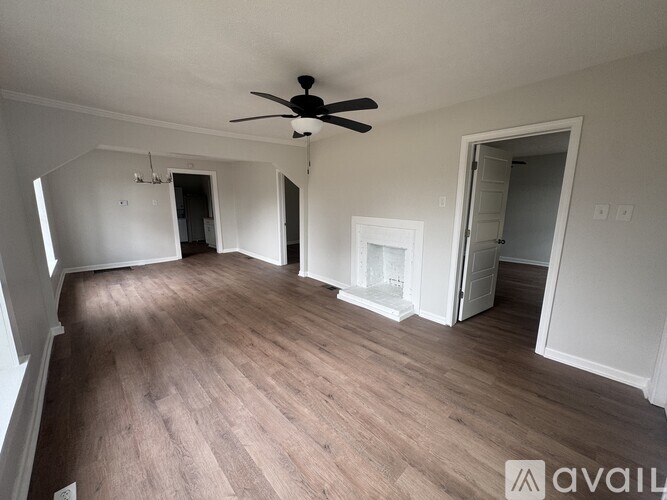 A spacious room with a ceiling fan and light wood flooring.