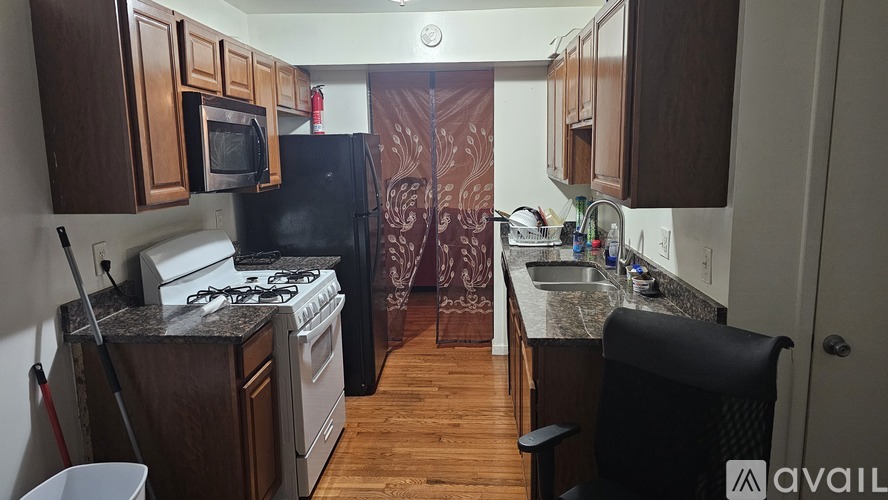 A kitchen with a black refrigerator, white stove, and wooden cabinets.