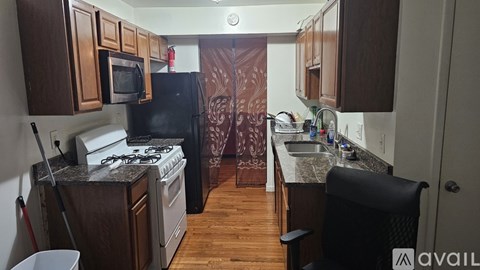 A kitchen with a black refrigerator, white stove, and wooden cabinets.
