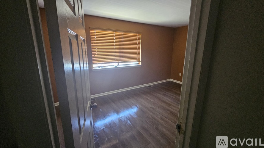 A room with wooden flooring and a window with blinds.