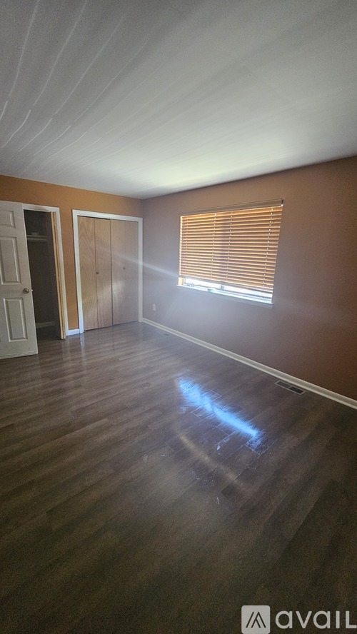 A room with wooden floors and a window with blinds.