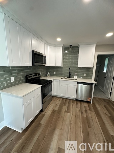 A kitchen with white cabinets and a wooden floor.