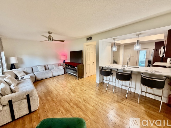A living room with a white couch and a green ottoman.