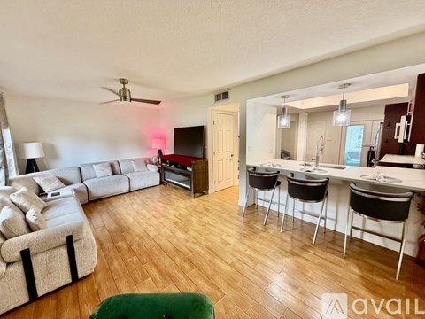 A living room with a white couch and a green ottoman.